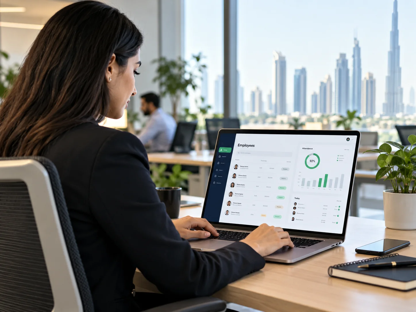 HR manager reviewing an employee directory and attendance dashboard on a laptop in a bright contemporary office, screen angled toward viewer