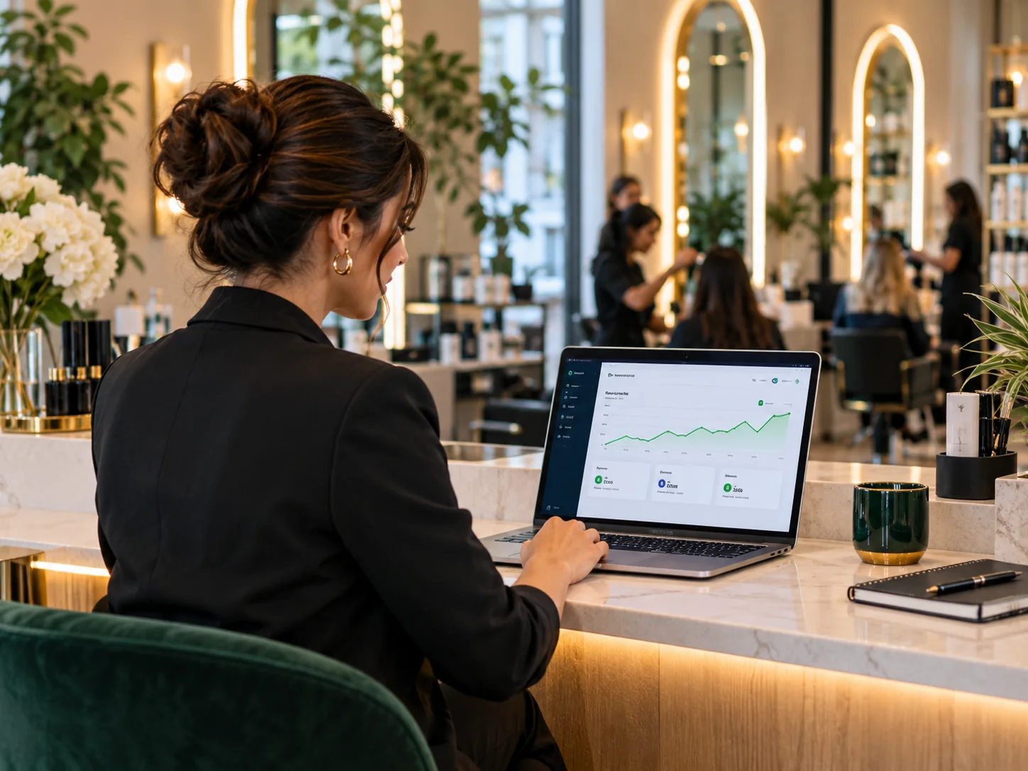Salon owner reviewing revenue analytics on a laptop at a reception desk, simple green line chart and customer metrics cards, tasteful interior